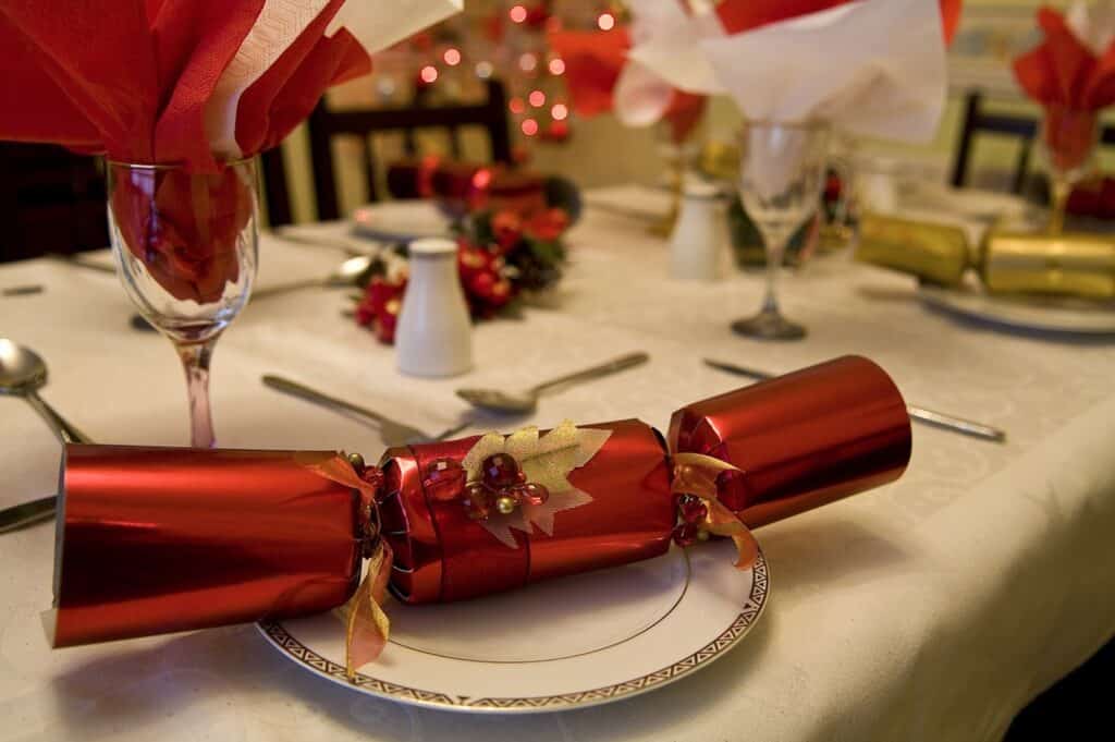 A holiday table scape with fancy holiday cracker gifts on the plate.