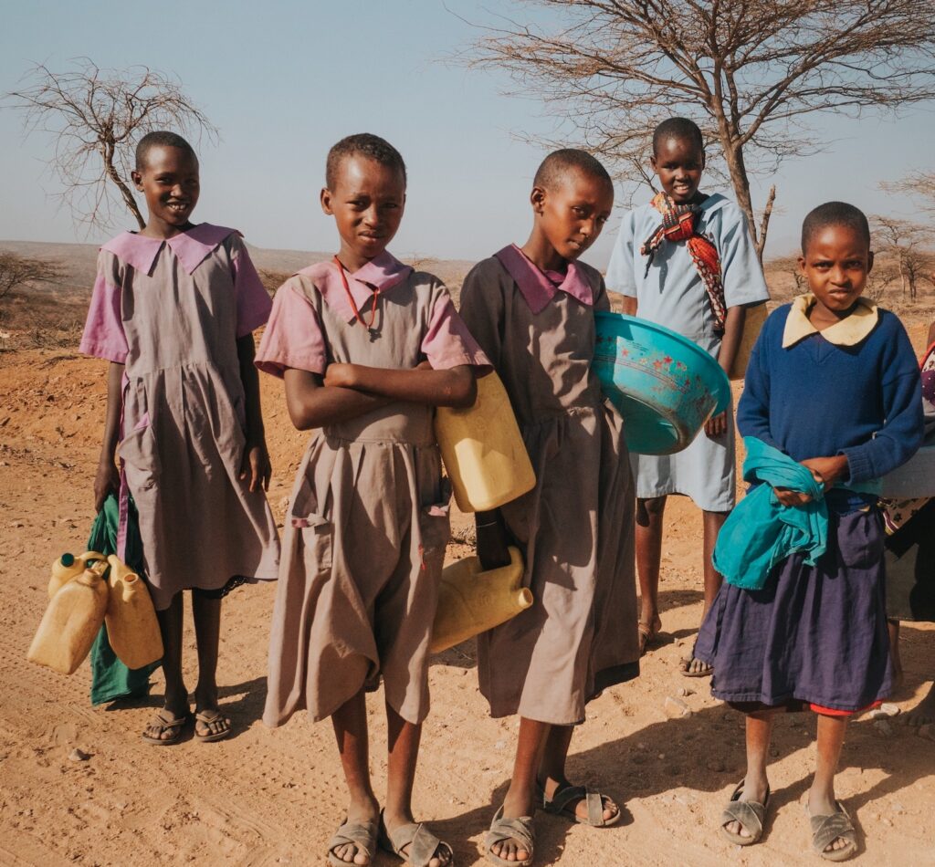 Children holding water containers in the Desert on a mission trip.